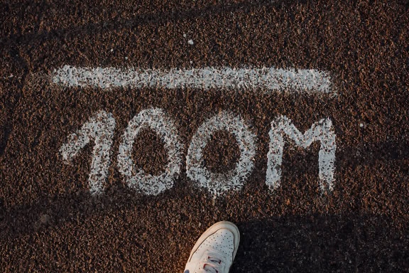 De voet van een persoon op de weg met een wit tekstbord 1000M, dat een lijn van duizend meter toont