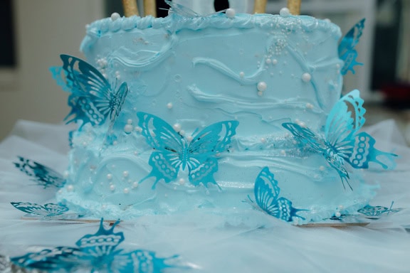 Cake with icing and with decoration in a shape of blue butterflies