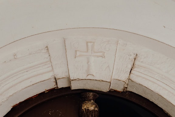 Arche en pierre blanche au-dessus de la porte d’entrée avec une croix sculptée