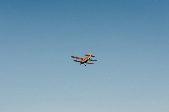 Un avión agrícola, un viejo avión biplano utilizado para fumigar vuela en el cielo azul