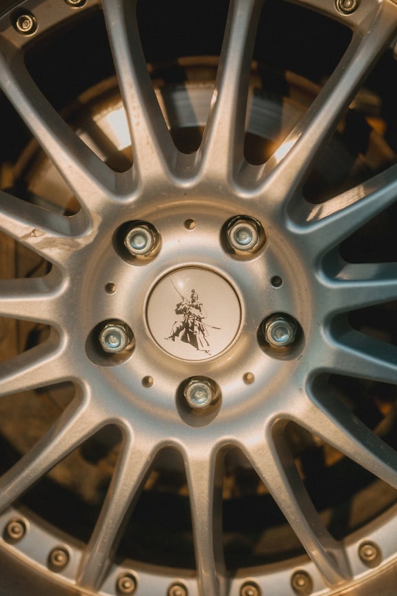 Glossy aluminum wheel of a car with a samurai sign, a close up of a shining rim with stainless steel screws