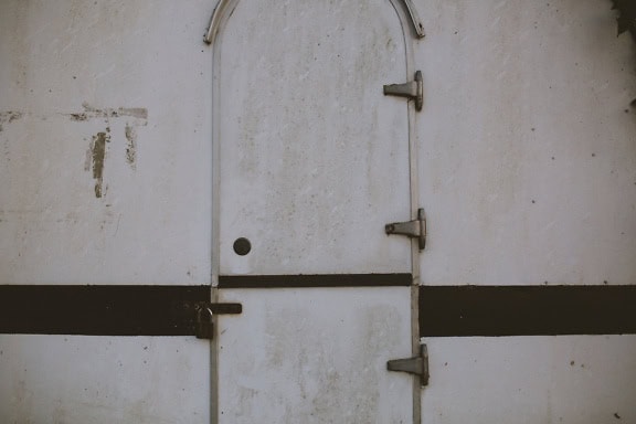 Dirty white door with padlock of an old camp trailer