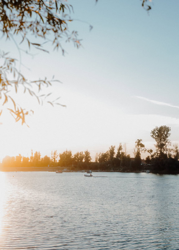 Piccola barca a motore sul lago Tikvara nel pomeriggio con raggi di sole luminosi come retroilluminazione, Backa Palanka