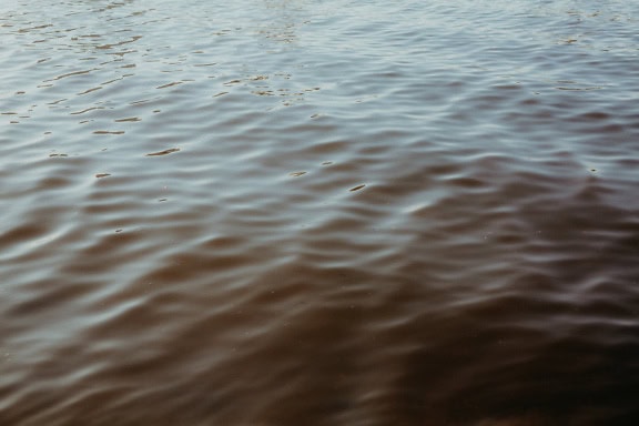 Texture de la surface de l’eau dans la demi-ombre avec des ondulations