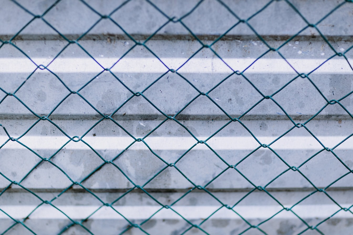 Textura de una valla de alambre verde oscuro con superficie de metal galvanizado con líneas horizontales como fondo