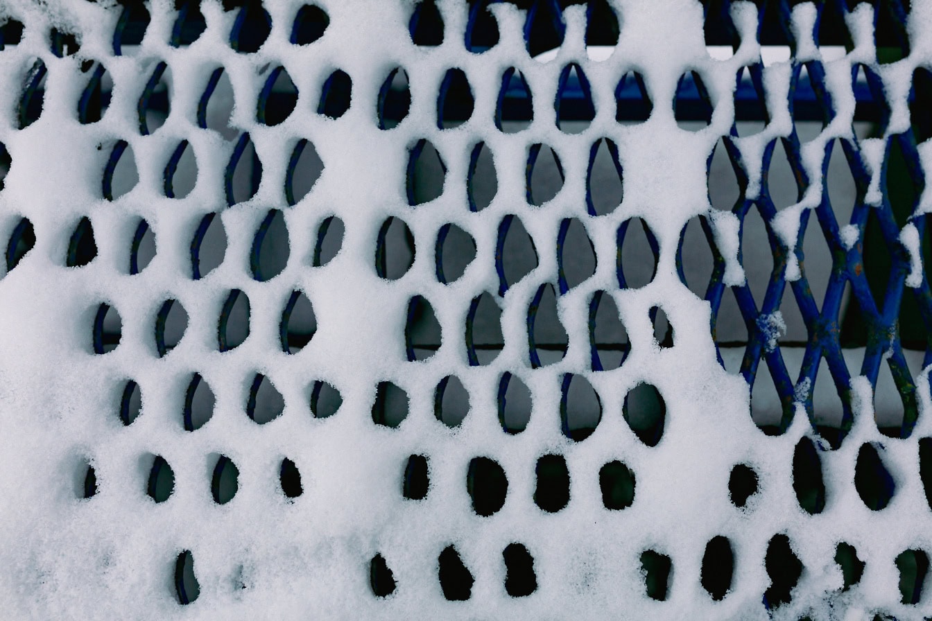 Close-up texture of snow on the surface of the metal grid