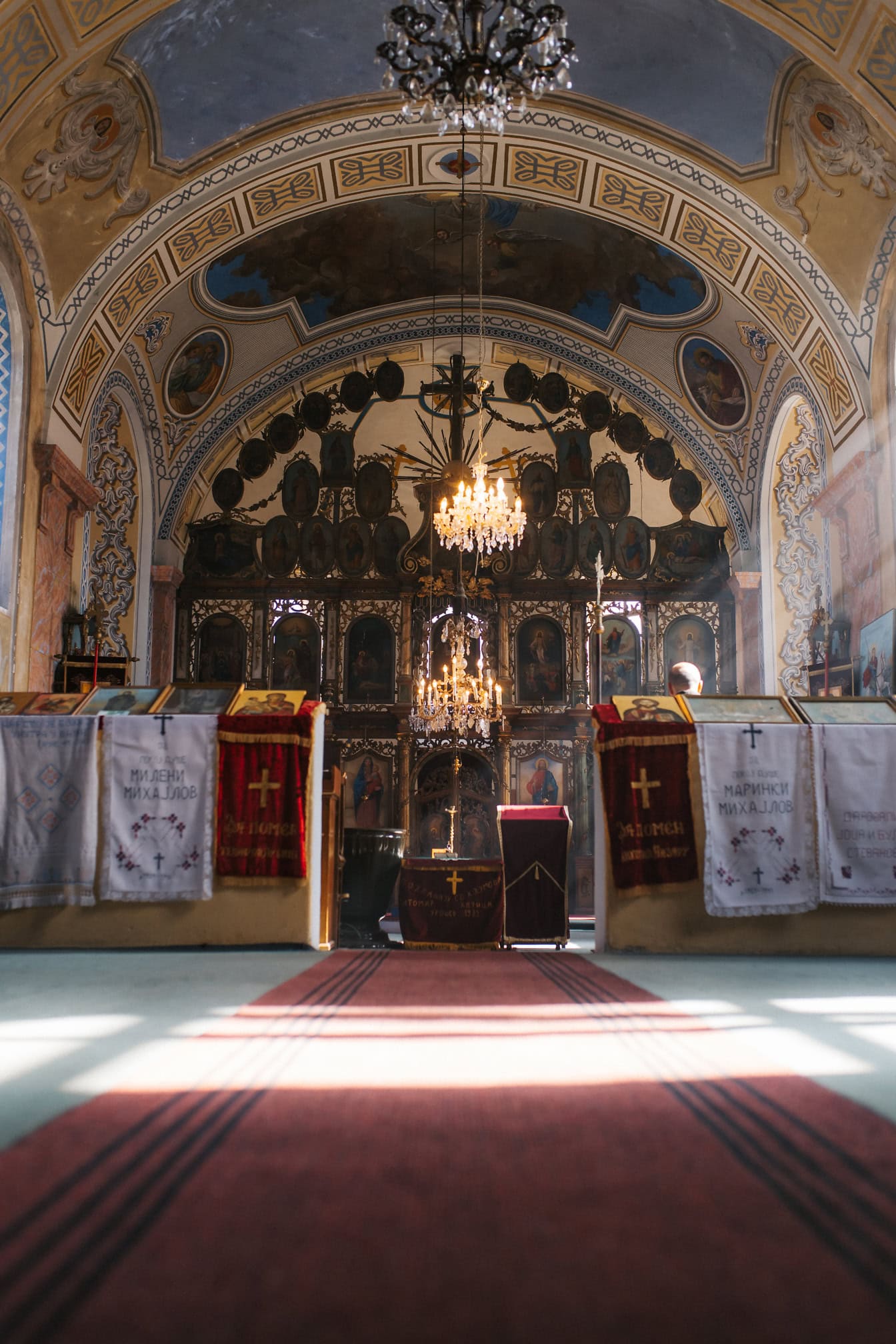 Et sakralt fotografi i lav vinkel av et kirkeinteriør med en lysekrone og med et alter med ikoner i bakgrunnen