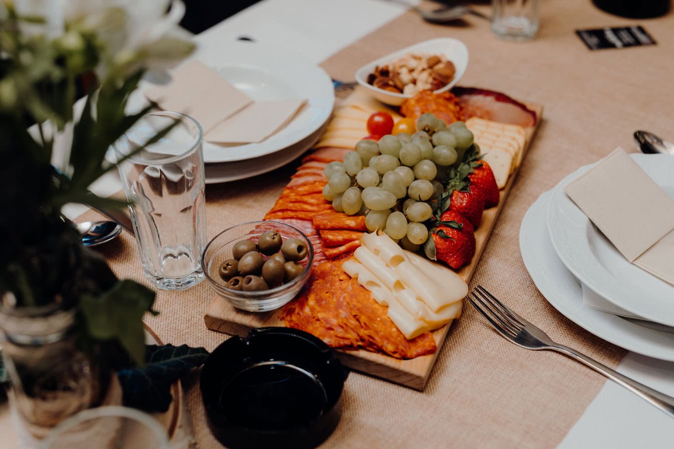 Aperitivo na mesa, linguiça de porco caseira com azeitonas, queijo, uvas brancas e morangos