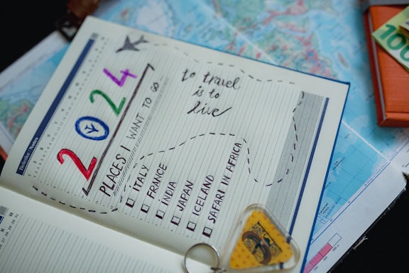 Notebook with a key on it and list of places to visit in 2024, a travel plan