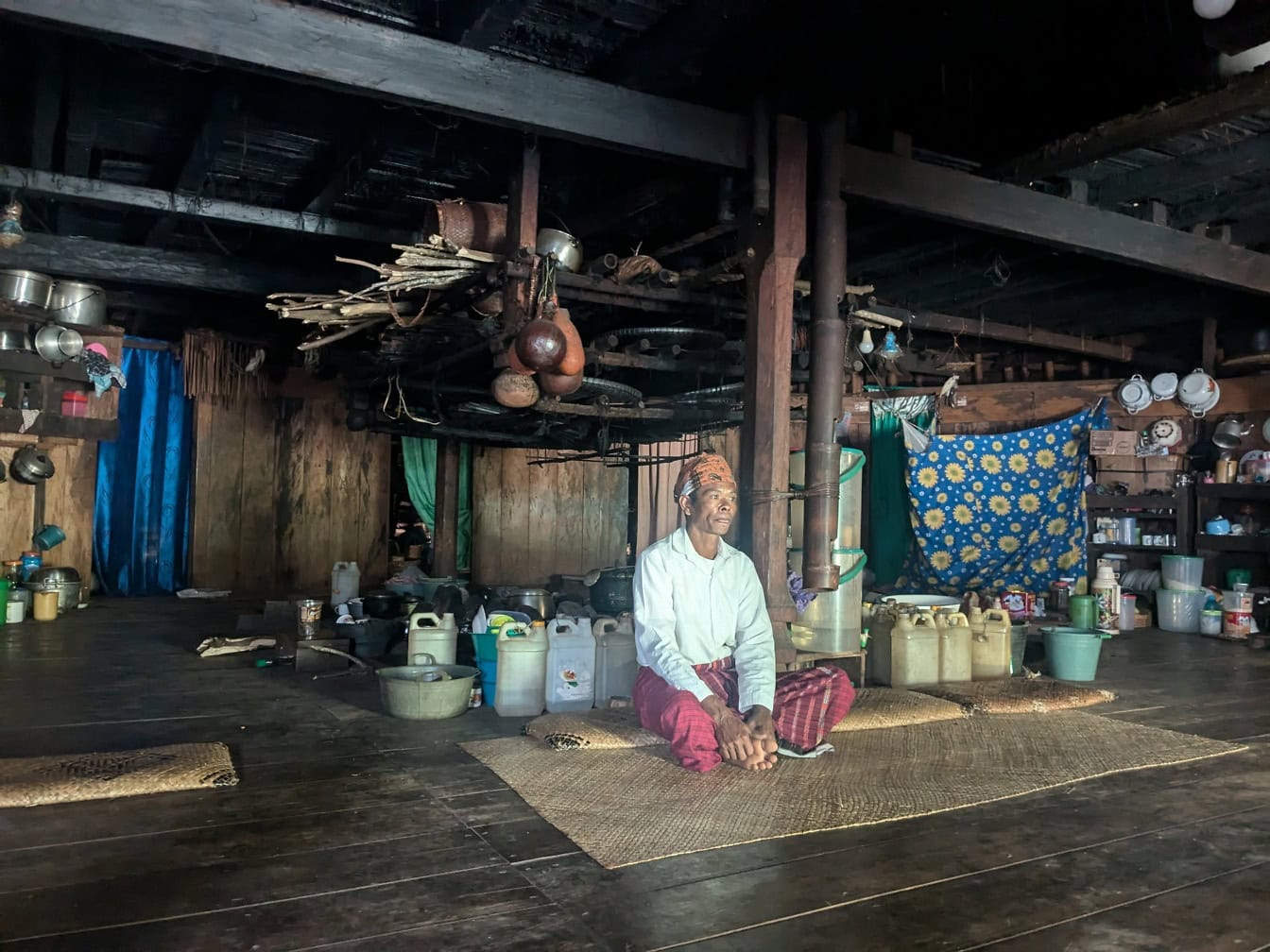 Mand sidder på en måtte i et traditionelt hjem i en etnolandsby på Bali, Indonesien