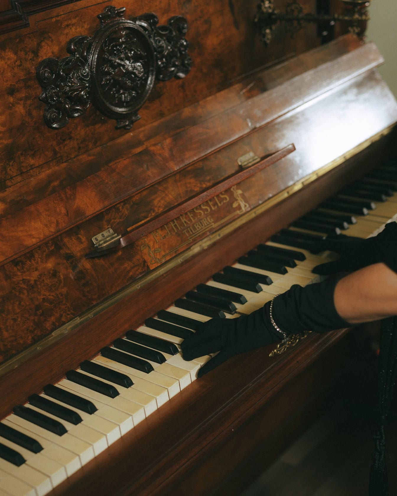 Close-up van een handen van een pianist in zwarte handschoenen die een barokke piano spelen