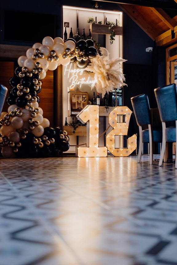 Balloon arch with Happy Birthday neon lights and number 18 in rustic-modern winery, a perfect place to celebrate an adulthood