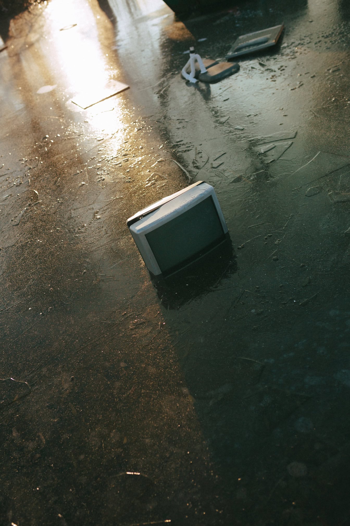 A water pollution with a old electric appliances, an old television receiver dumped in a frozen lake with other garbage