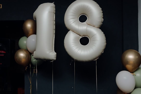 Una festa di compleanno con un palloncino ad elio a forma di numero diciotto (18)