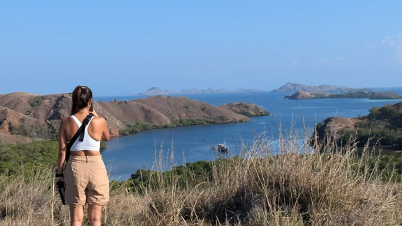 Donna in piedi su un punto panoramico su una collina che domina una baia