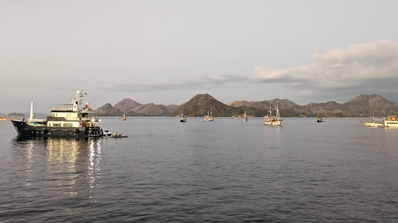 Fishing boats on the water with mountains in the background