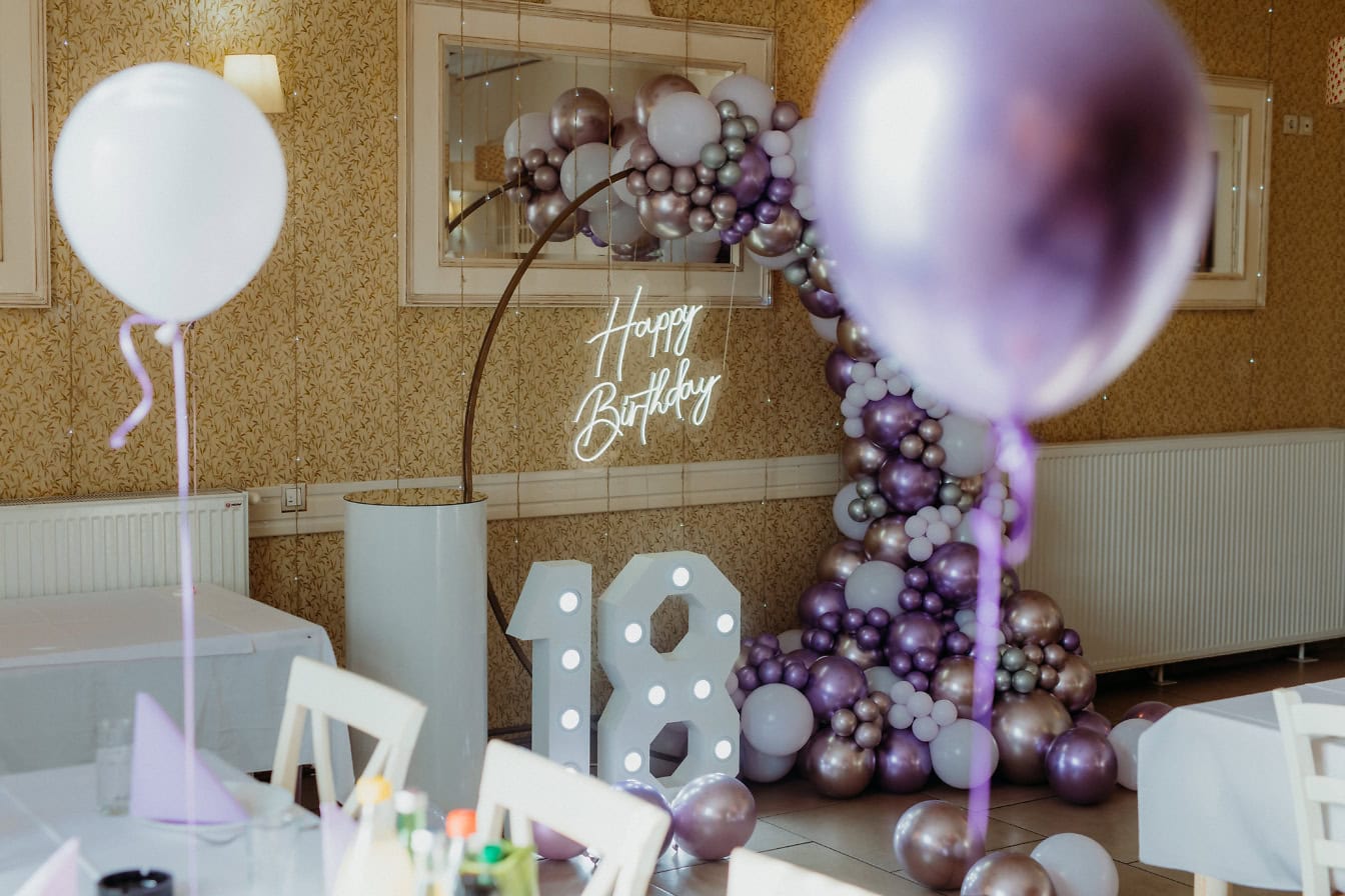 Chambre avec arche de ballons et une enseigne Joyeux anniversaire au néon