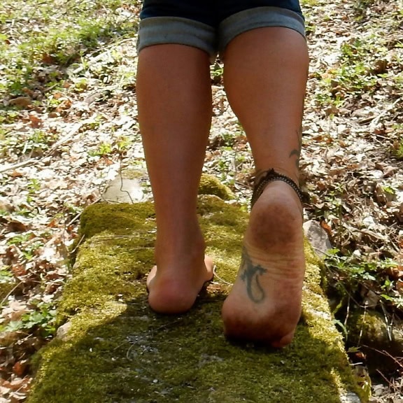 Barefoot man walking on a mossy rock