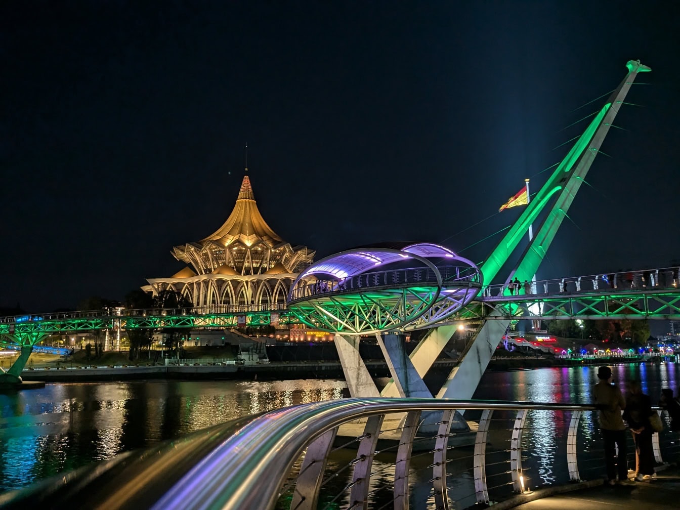 Puente sobre el agua con un edificio de la Asamblea Legislativa del Estado de Sarawak al fondo, Kuching, Malasia