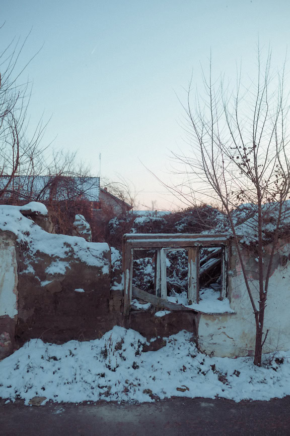 Uma velha casa abandonada e arruinada sem telhado e com paredes desmoronadas cobertas de neve