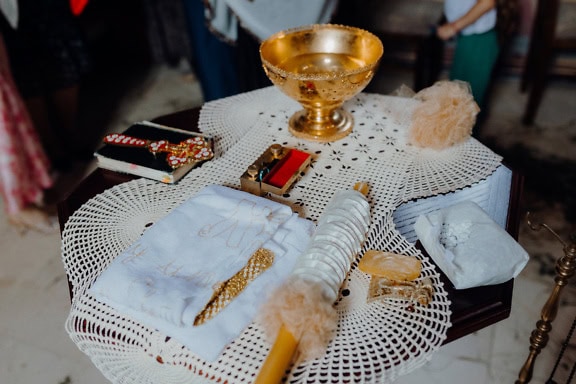 Bord med en gyllene skål, bibel och andra religiösa föremål som används under en ortodox kristen dopceremoni