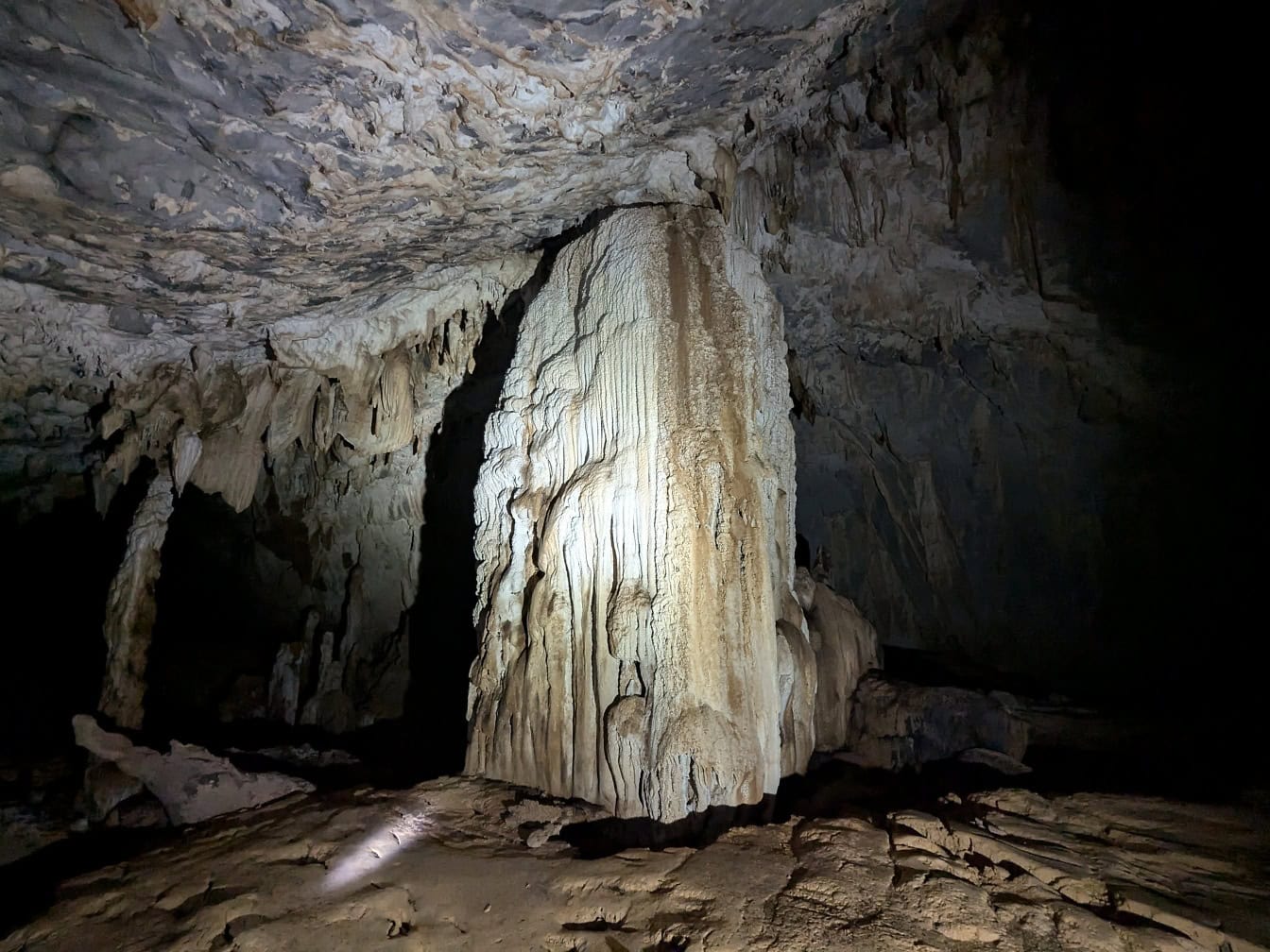 Velký skalní pilíř vyrobený z minerálního krápníku v podzemní jeskyni Lang v národním parku Gunung Mulu, Borneo, Malajsie