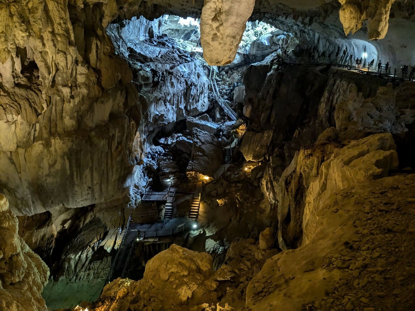 Uma foto de alto ângulo de rochas iluminadas em uma caverna subterrânea com uma passarela, reserva natural de Bornéu, Malásia