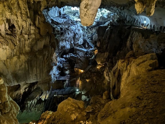 Foto sudut tinggi dari bebatuan yang diterangi di gua bawah tanah dengan jalan setapak, cagar alam Kalimantan, Malaysia