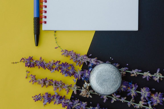 Vieille horloge analogique, une montre de poche et un cahier avec un stylo sur une surface jaune et noire