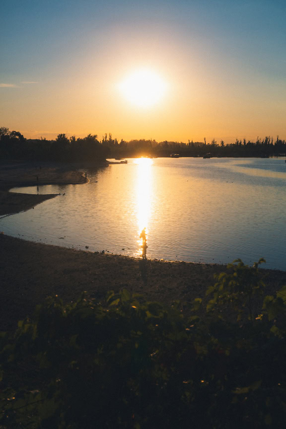 Kalastajan siluetti Tikvara-järven vedessä Backa Palankassa auringonlaskun aikaan