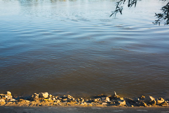 Tepi sungai Danube dengan batu dan jejak kaki di pasir