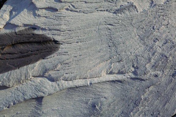 Primo piano di una roccia arenaria grigia con macchia di olio motore su di essa