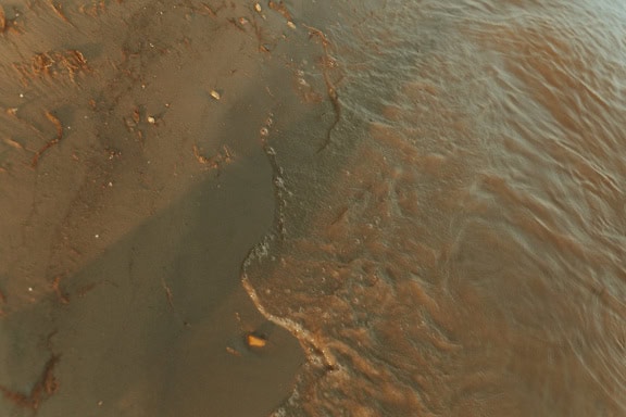 Areia molhada e rochas em uma praia