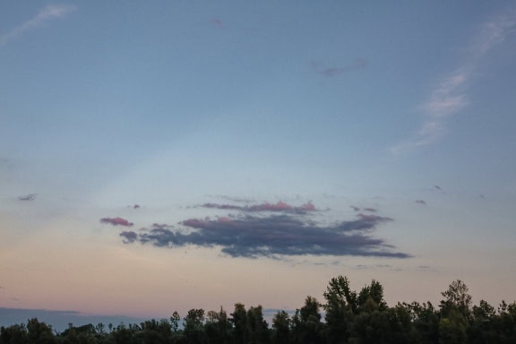 夕暮れ時の青空の下、遠くに浮かぶ木々