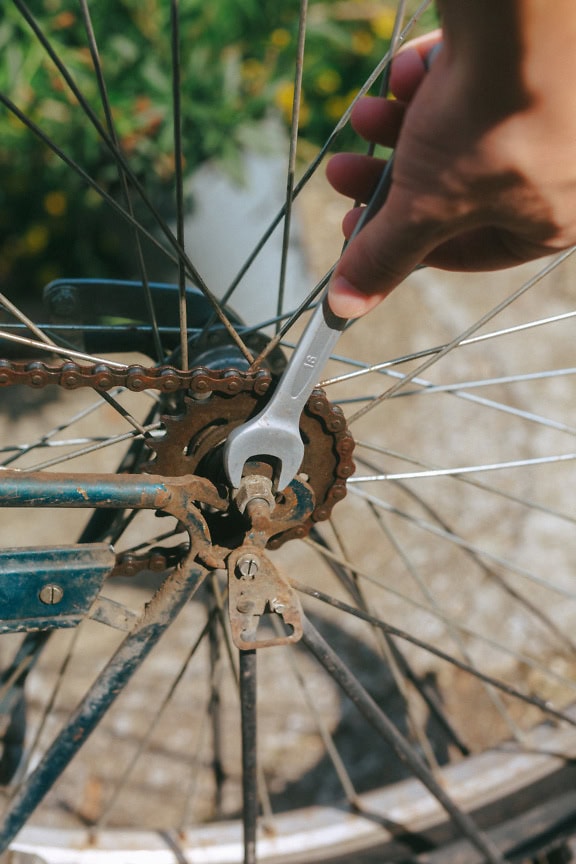 Mâna unui meșter de bicicletă care ține cheia și repară echipamentul unei biciclete