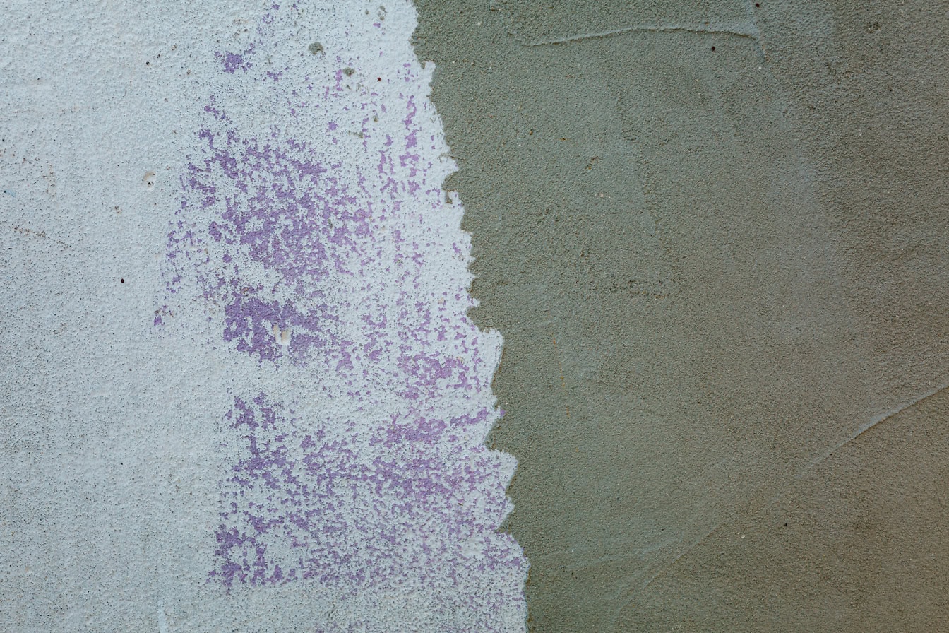 Mur en ciment à moitié peint avec de la peinture blanche et de la peinture violette par-dessus, texture de mur de ciment avec de la peinture