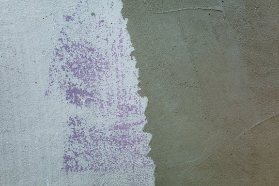 Cement wall half painted with white paint and purple paint over it, cement wall texture with paint