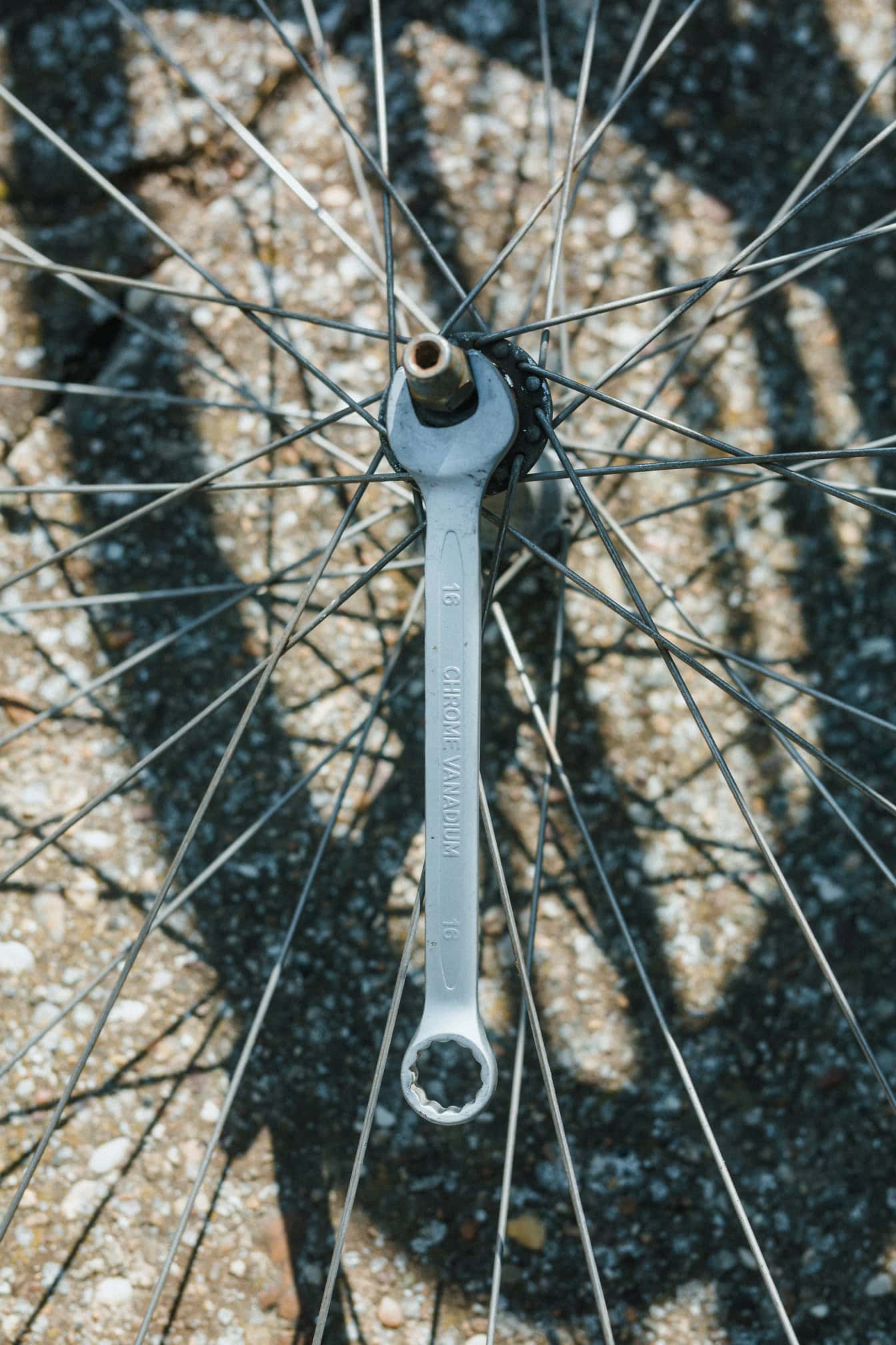 De chroom-vanadiummoersleutel van een monteur op een fietswiel met stalen moer