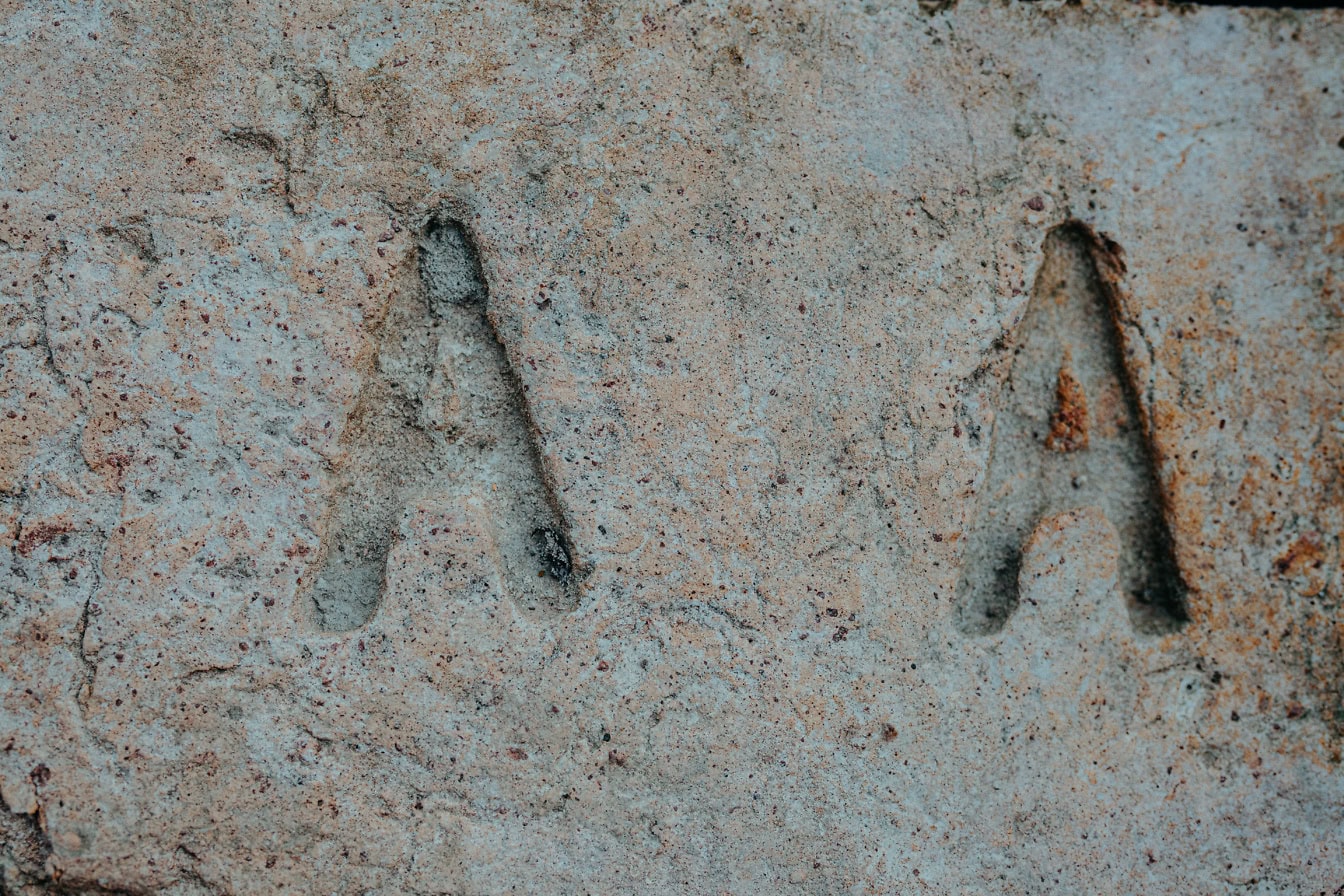 A close-up of an old brick with a imprint of the letter A