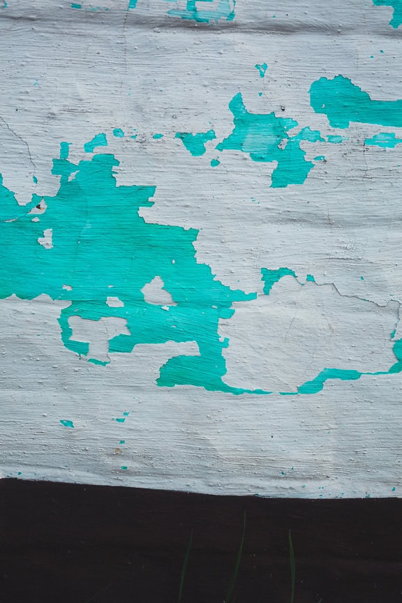 Textura de una pared pintada con pintura de cal verde turquesa y pintura blanca sobre ella