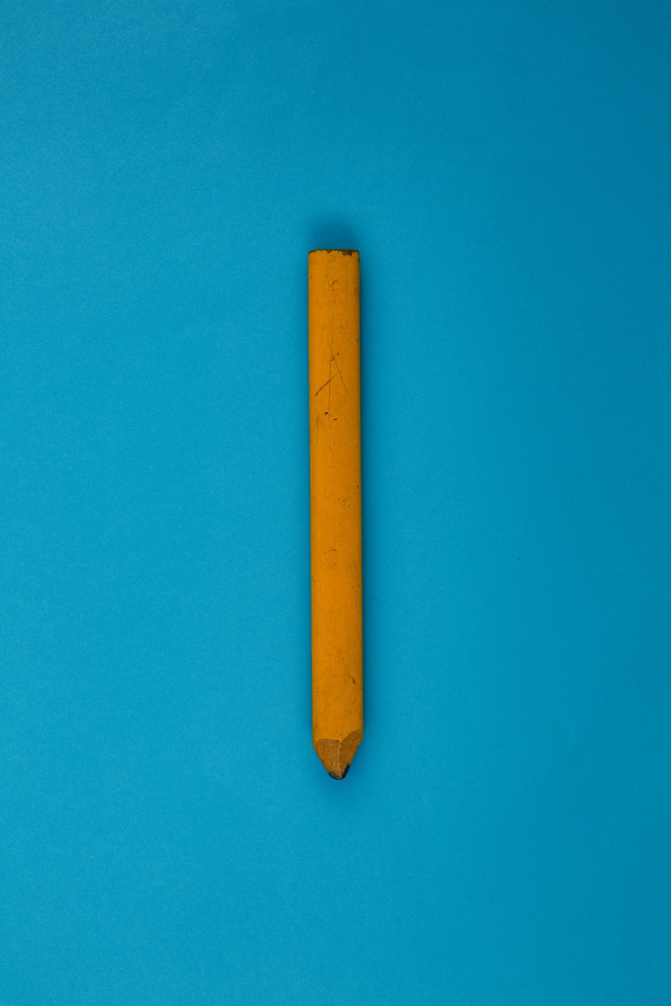 Yellowish brown wooden pencil on a blue surface