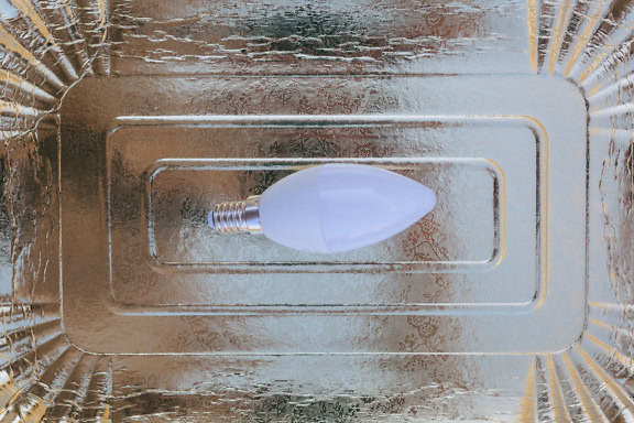 An energy-saving lightbulb with light emitted diode on grey shining and reflective surface