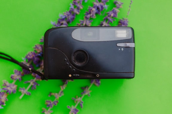 Vecchia fotocamera analogica nera su una superficie verde