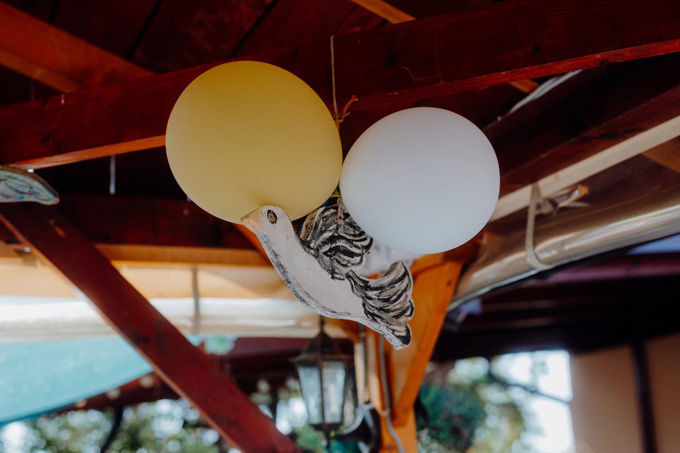 Hengende dekorasjon av hvit fugl med to ballonger under tak