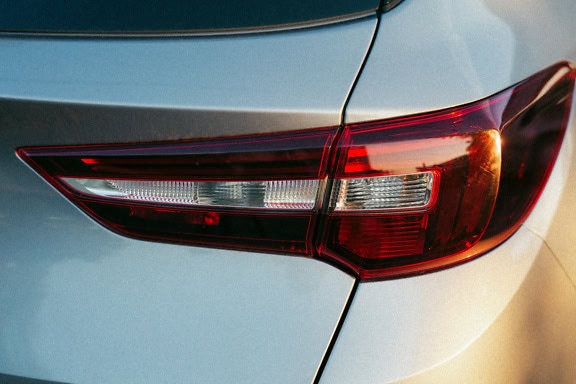 The back of a white car with a trunk and red brake light