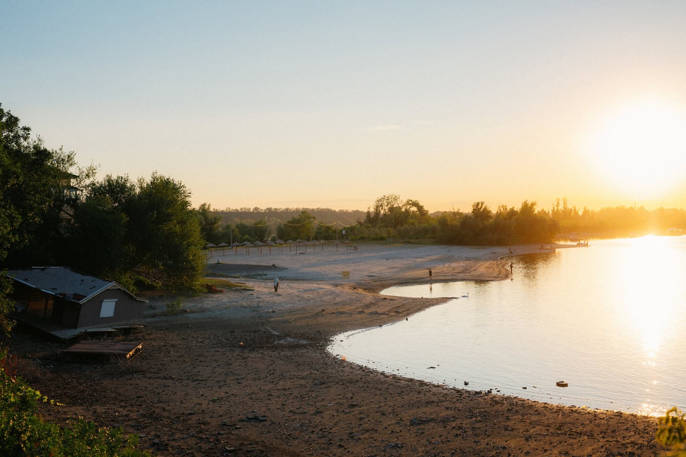 Sonnenuntergang am Strand des Tikvara-Sees in Bačka Palanka mit einem schwimmenden Haus, das bei niedrigem Wasserstand am Ufer gestrandet ist