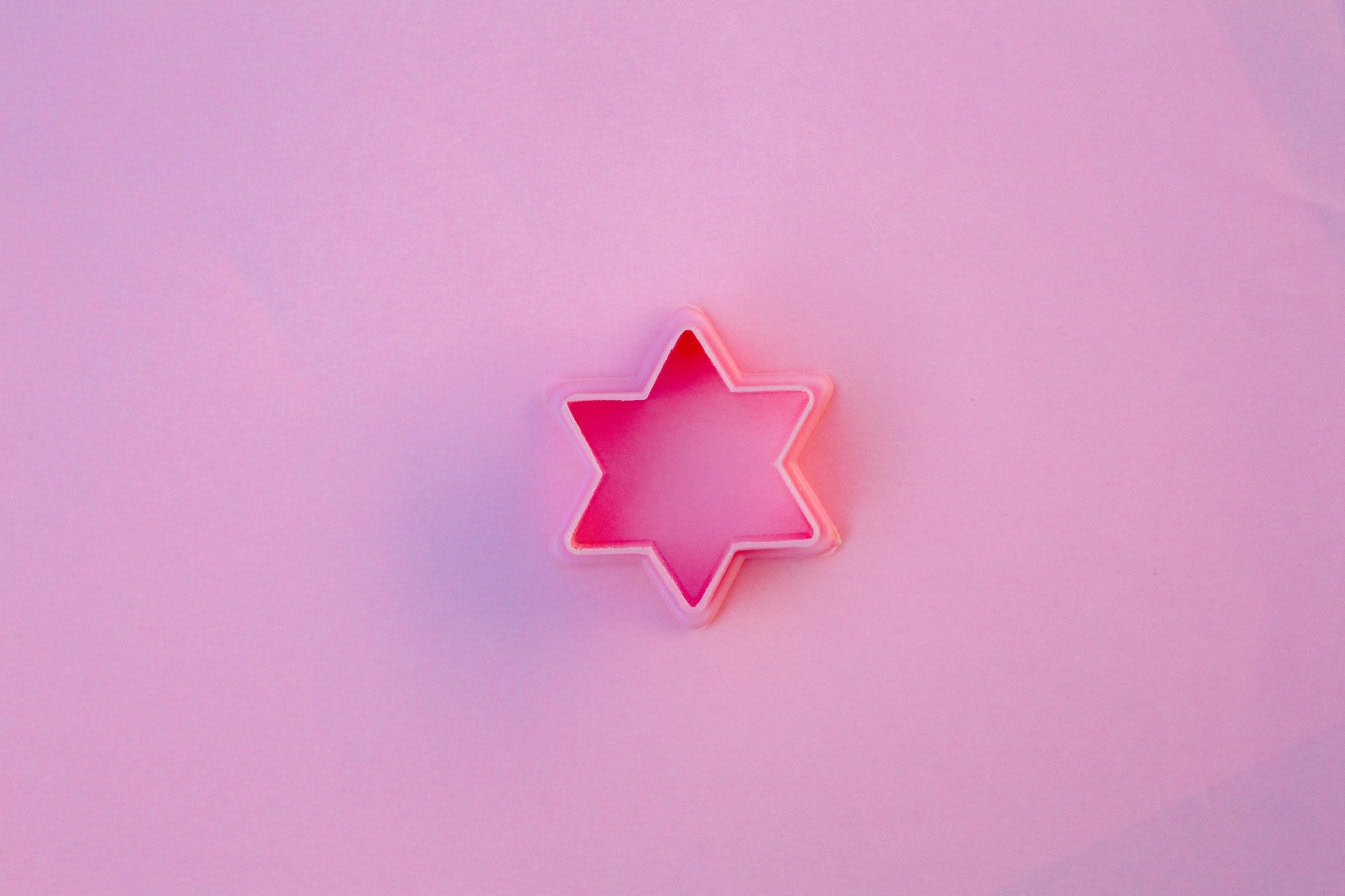 Cortador de galletas rosa de plástico en forma de estrella sobre un fondo rosado