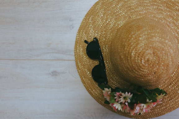 Yellowish straw hat with sunglasses and flowers on it