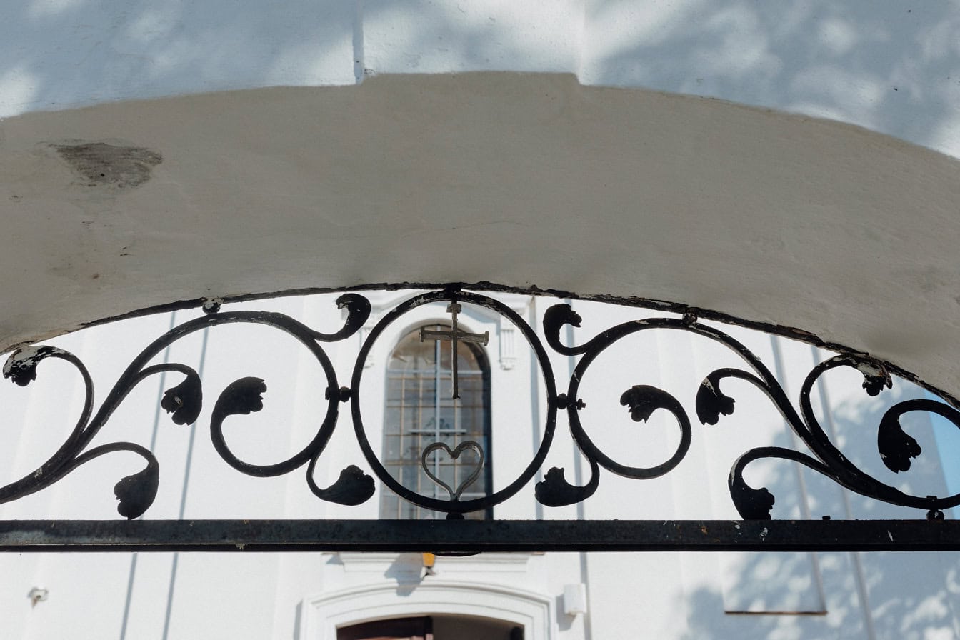 Una puerta de metal fundido con un corazón y una cruz debajo del arco