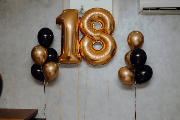 Balon helium emas dan hitam berbentuk nomor delapan belas (18) sebagai dekorasi pesta ulang tahun